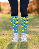 Rubber Ducky riding boot socks worn over navy breeches with white sneakers, blue duck print showing at the calf