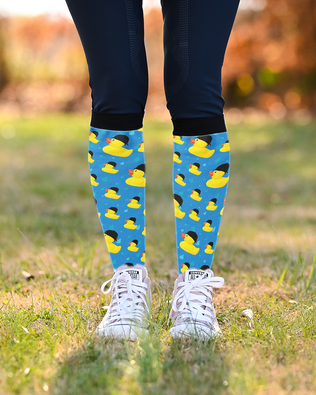 Rubber Ducky riding boot socks worn over navy breeches with white sneakers, blue duck print showing at the calf