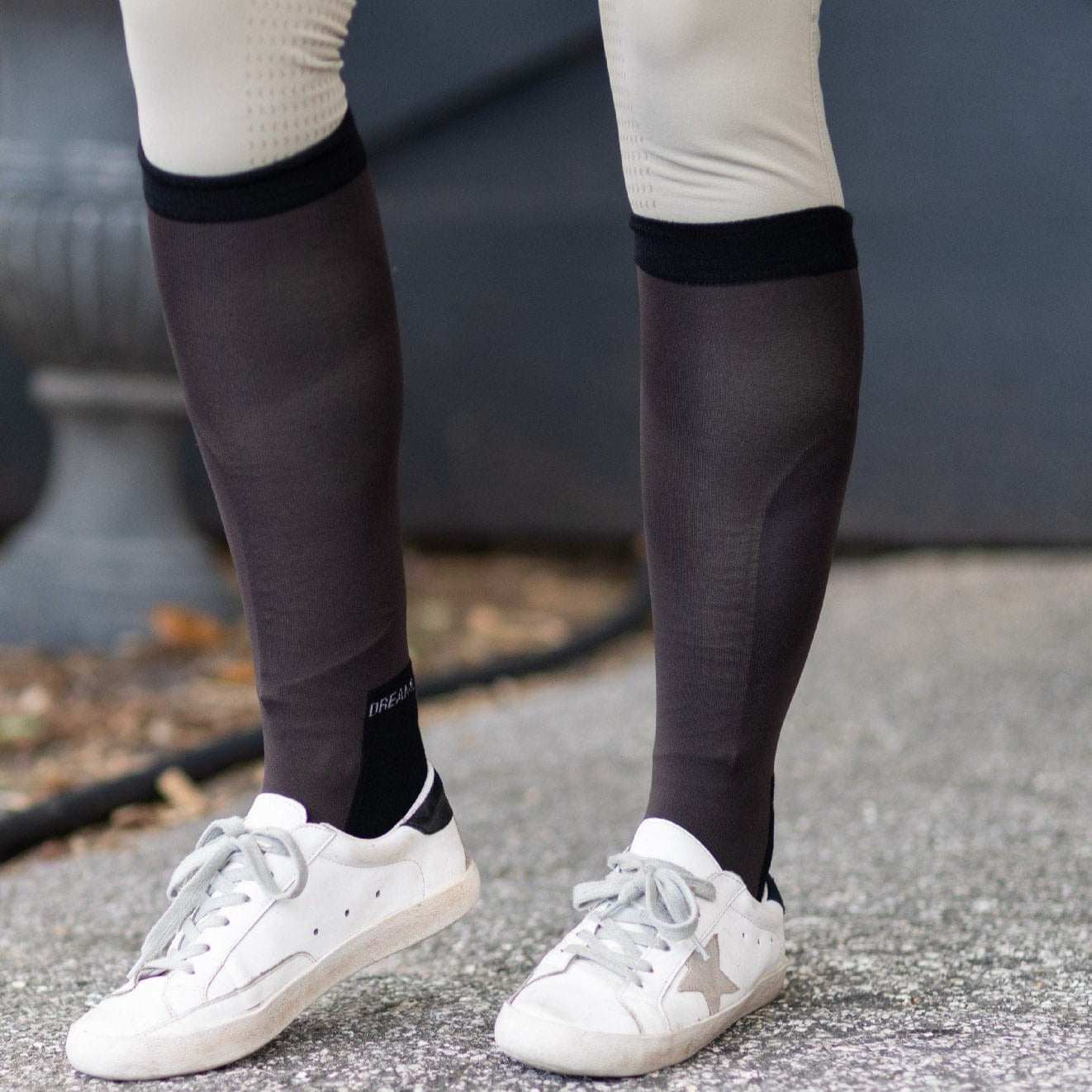 close-up of brown equestrian boot socks worn with white sneakers and beige riding pants