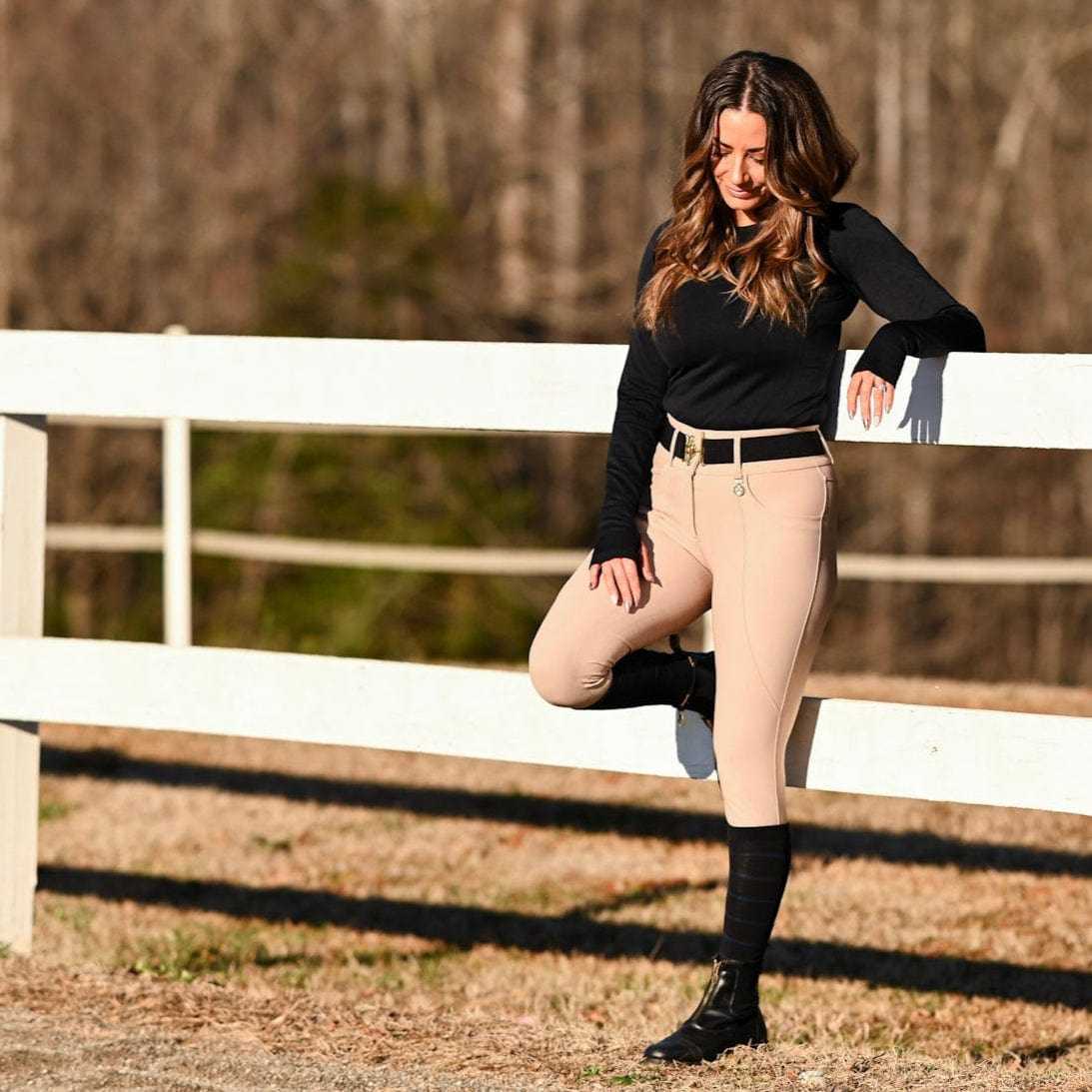 woman wearing knit boot socks with equestrian outfit outdoors near white fence
