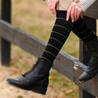 Person wearing black striped knit boot socks with black equestrian boots outdoors