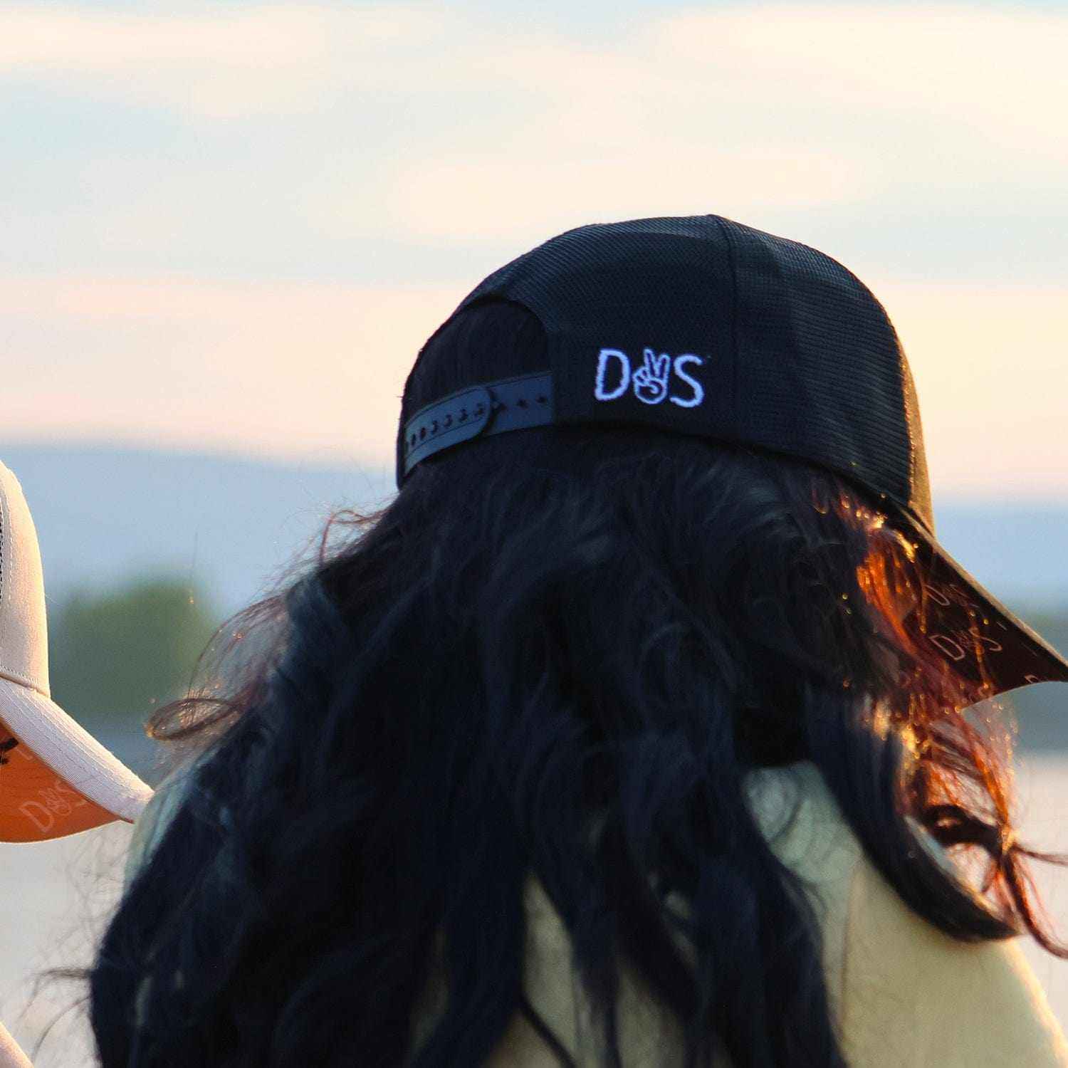 Stall Rest Equestrian Bundle black trucker hat worn by person with long hair outdoors at sunset