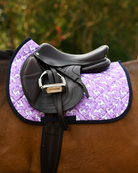 Sunshine & Unicorns pad in lilac under a brown close-contact saddle with stirrup and girth