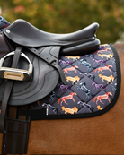 Angled view of the Horse Skeletons saddle pad beneath a brown saddle and stirrup on a bay horse