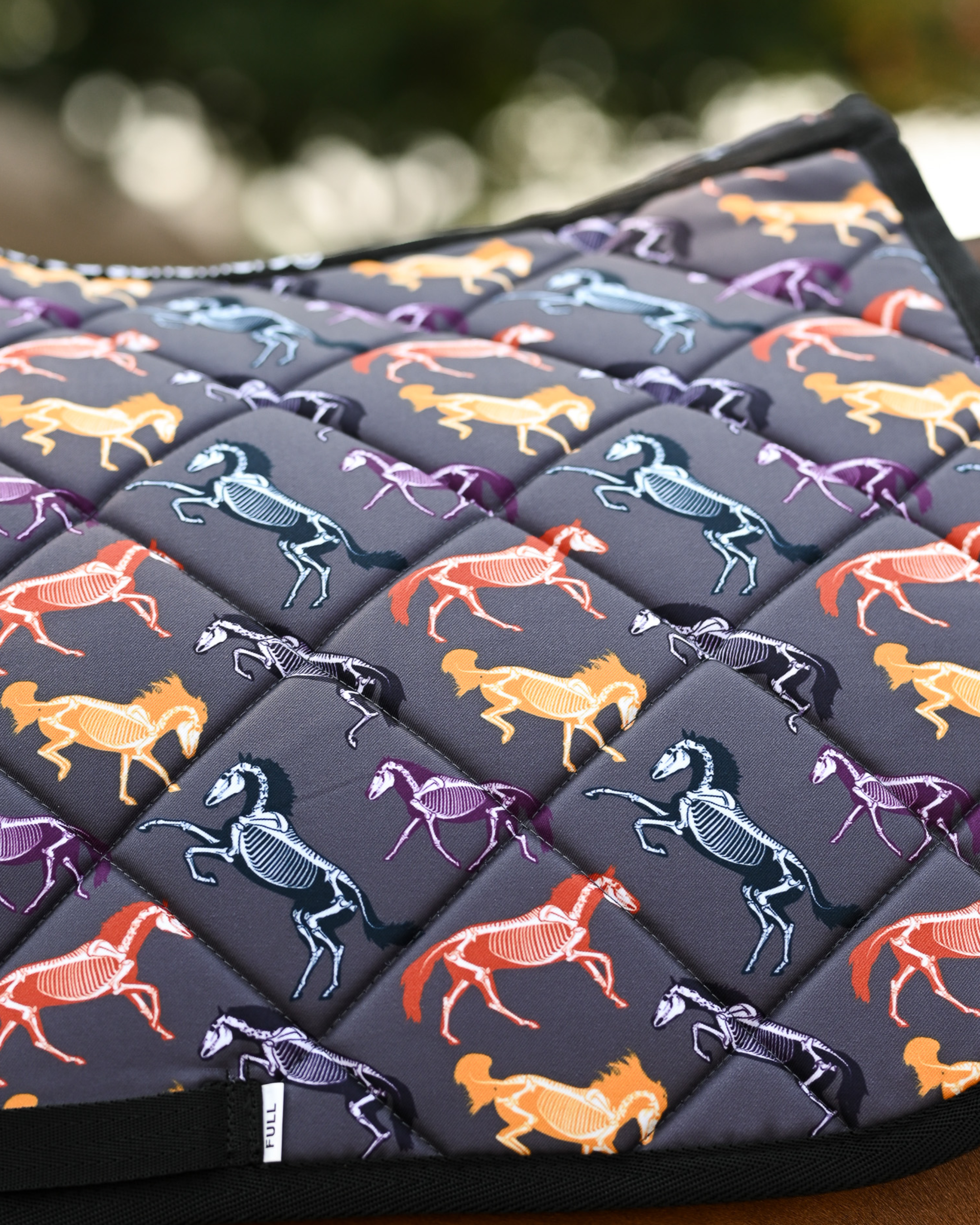 Close crop of the Horse Skeletons print: orange, purple and teal skeletons over grey quilting